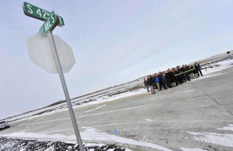 -Messenger photo by Hans Madsen Framed by the new street signs for First Avenue South and South 42nd Street, a group braves frigid single digit temperatures Thursday morning to cut the ribbon for the new Decker Development Park on the east side of Fort Dodge.